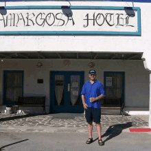 a man stands in front of a white building that says margosa hotel