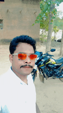 a man wearing sunglasses stands in front of a black honda motorcycle