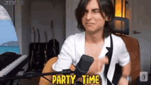 a man is playing a guitar in front of a microphone and says `` party time '' .