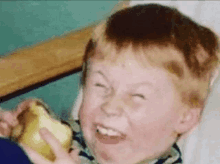 a young boy is making a funny face while holding a piece of cheese .