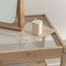 a candle is sitting on a glass table next to a mirror and earrings .