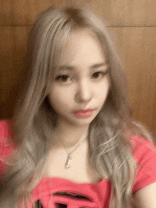 a girl with blonde hair is wearing a pink top and necklace