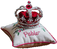 a red crown sits on a white pillow with pablo embroidered on it