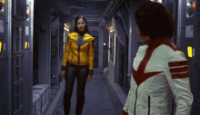 a woman in a yellow jacket is standing next to another woman in a white and red jacket