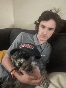 a man wearing a grey shirt that says city is holding a small dog