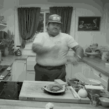 a black and white photo of a man in a kitchen with a cutting board that says bos on it