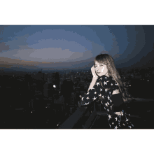 a woman standing on a balcony looking out over a city