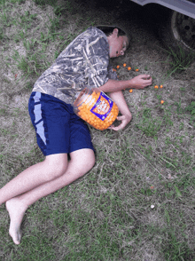 a boy is laying on the ground with a jar of cheese balls