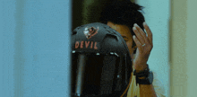 a man is putting on a helmet with the word devil on it