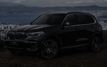 a black bmw the x5 is parked on a hillside