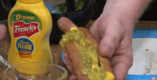 a bottle of french 's classic yellow mustard next to a person 's hand