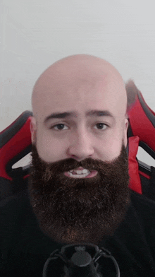 a bald man with a beard and mustache is sitting in a red chair