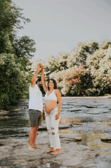 a man and a pregnant woman are dancing in the water