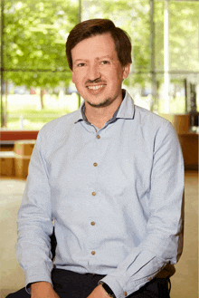 a man wearing a light blue shirt is smiling