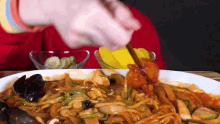 a person is eating a plate of noodles and meat with chopsticks