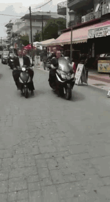 a group of people riding scooters down a street in front of a sign that says ' ice cream '