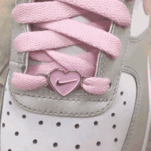 a close up of a pair of nike shoes with pink laces and a pink heart shaped nike logo .