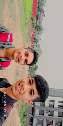 two young boys are smiling in front of a building with the date of aug 3 2022 at 6:05 pm