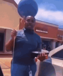 a man is holding a blue balloon on top of his head while standing in front of a store .