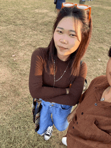 a woman with her arms crossed stands next to another woman in a field