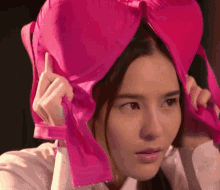 a woman is holding a pink bra over her head .