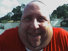 a man in a red shirt is smiling with a very large chin