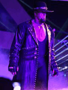 the undertaker is wearing a cowboy hat and a long black coat .