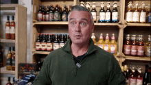 a man stands in front of a shelf full of bottles of alcohol including one that says ' strawberry '