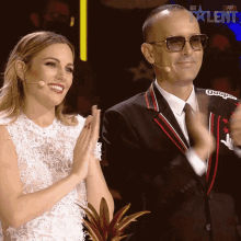 a man in a suit and a woman in a white dress are clapping in front of a screen that says got talent