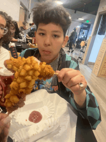 a boy is eating a fried chicken stick with ketchup on it