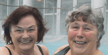 two older women are smiling for the camera in a swimming pool