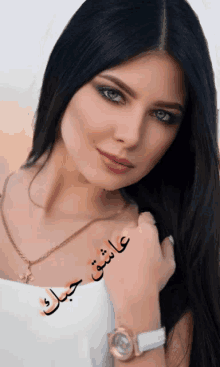 a woman wearing a watch and a necklace with arabic writing on it