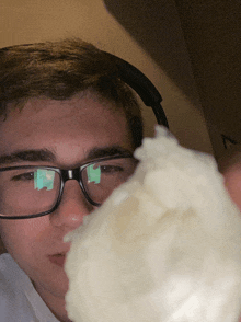 a young man wearing glasses and headphones looks at a white object