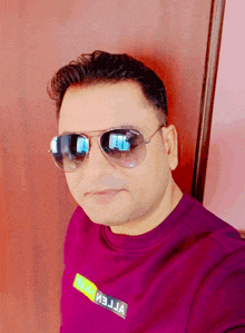 a man wearing sunglasses and a purple shirt with the word reliance on the front