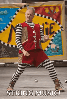 a man in striped pants and a red vest is dancing in front of a banner that says string music