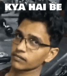 a young man wearing glasses is making a funny face with the words kya hai be written above him .