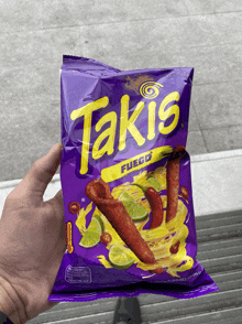 a person holding a bag of takis fuego chips