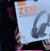 a person holding a zen hybrid pro headphones box