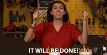 a woman in a red shirt is holding a hammer in front of a sign that says it will be done