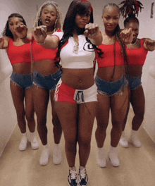 a group of women in shorts and crop tops pointing