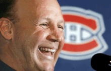 a man is smiling in front of a montreal canadiens logo