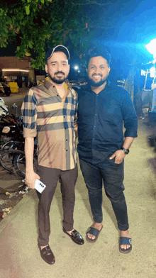 a man in a plaid shirt stands next to a man in a black shirt