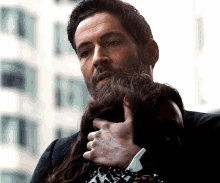 a man with a beard is holding a woman 's hair