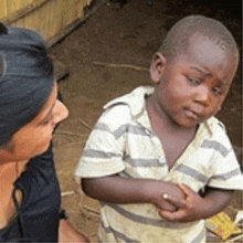 a woman is talking to a young boy wearing a striped shirt