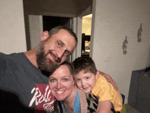 a man and woman are posing for a picture with a child wearing a shirt that says " rock "