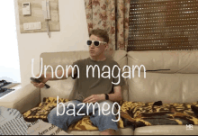 a man wearing sunglasses sits on a couch with the words " unom magam bazmeg " written on the bottom