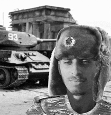 a black and white photo of a man wearing a fur hat in front of a tank with the number 93 on it