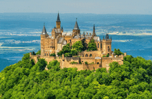 a large castle sits on top of a lush green hillside