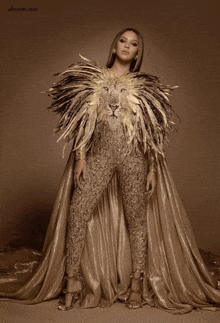 a woman in a gold jumpsuit with a lion embroidered on her cape