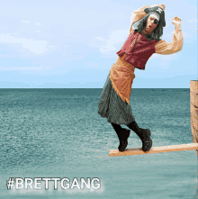 a man dressed as a pirate is balancing on a wooden board in the ocean